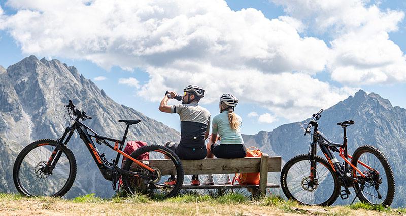 Mountainbiker machen Pause auf einer Bank mit Bergblick